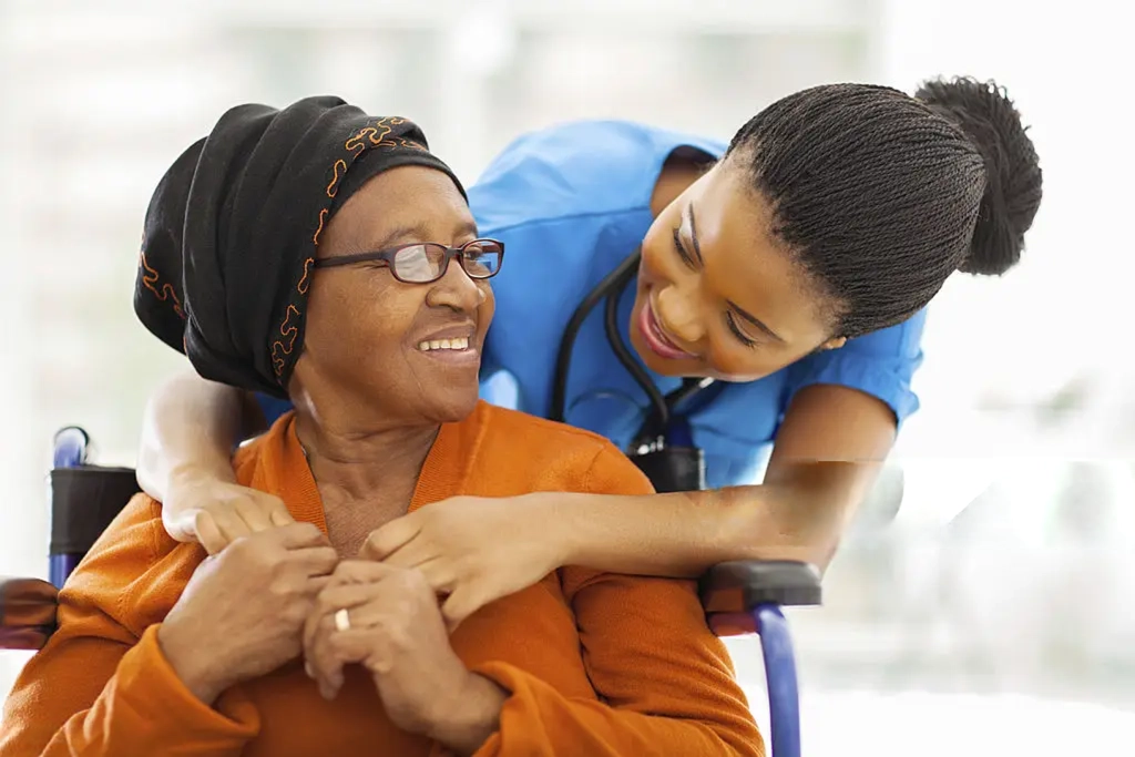A Reliance Homecare nurse comforting a smiling elderly client at home